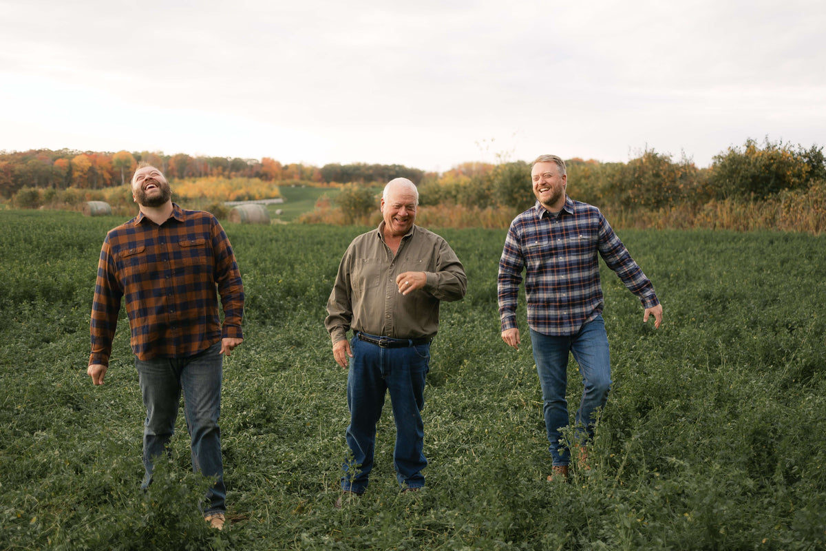 peterson brothers and farmer wayne smiling and laughing in a field