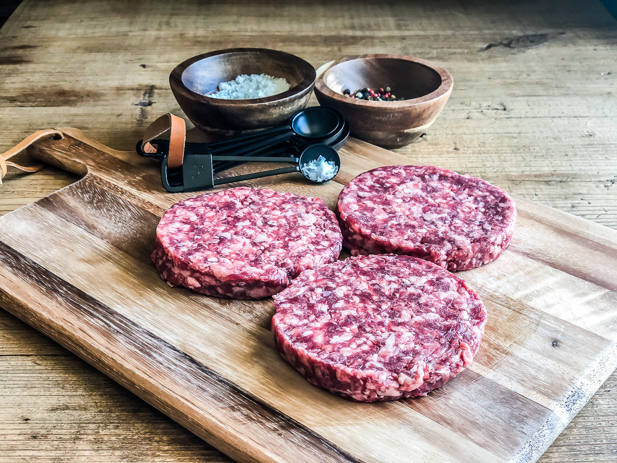 dry aged, beef patties on wooden cutting board with spices